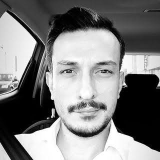 Araç içinde çekilmiş siyah-beyaz portre; beyaz gömlekli kişi emniyet kemerli